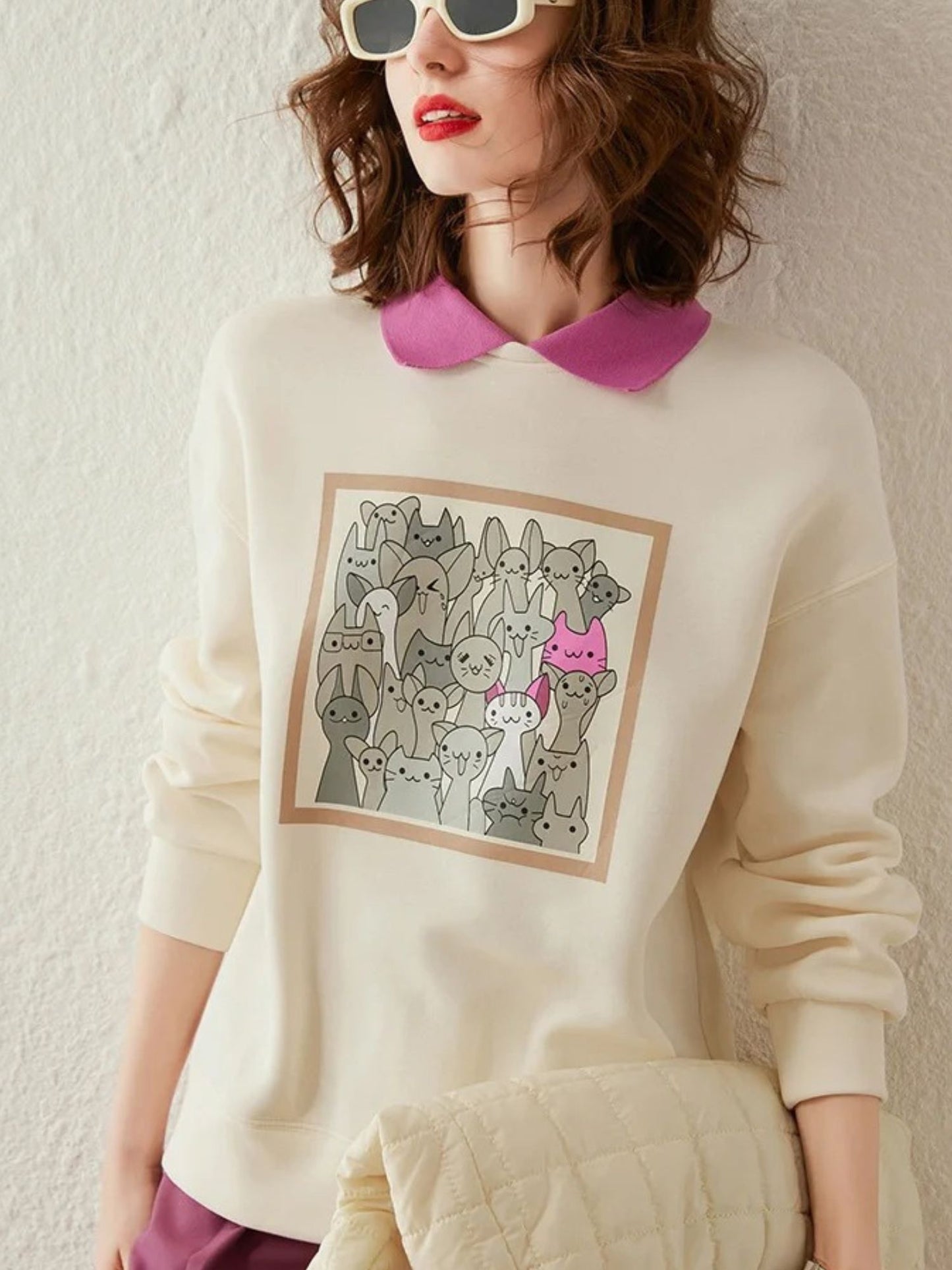 Front view of ivory graphic sweatshirt paired with collared shirt and skirt
