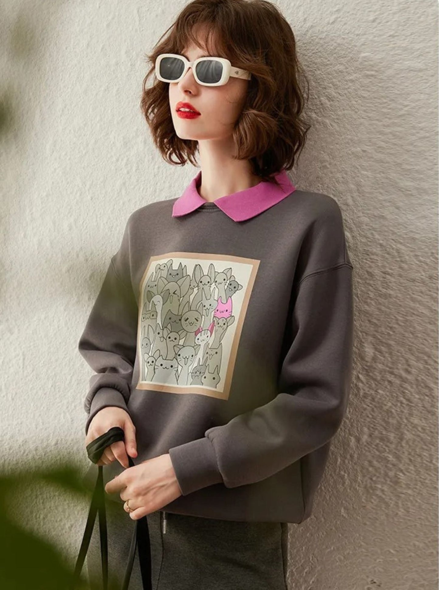 Side view of grey graphic print sweatshirt layered with pink collared shirt