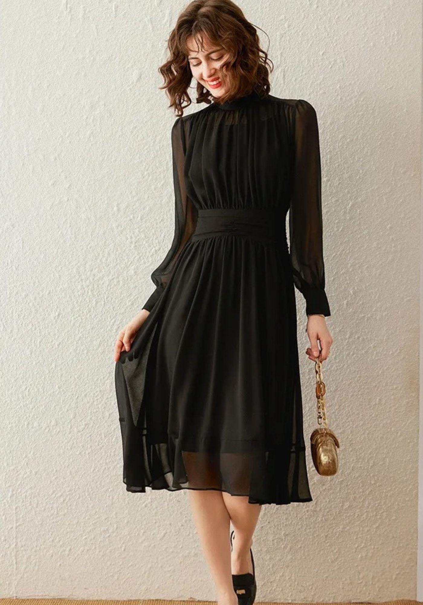 Front view of black pleated midi dress with high neck and long sleeves