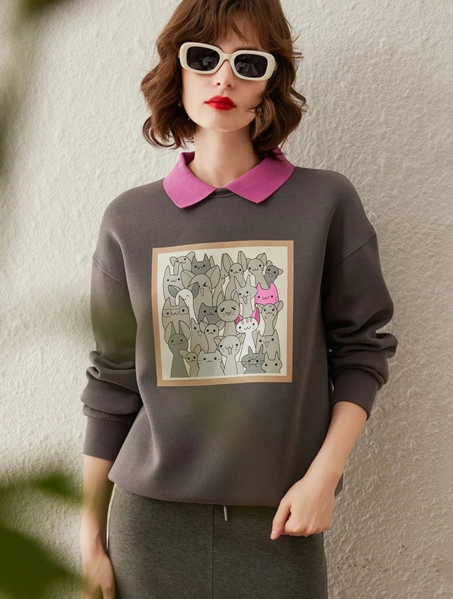 Woman in grey sweatshirt with printed front design, hands in pockets