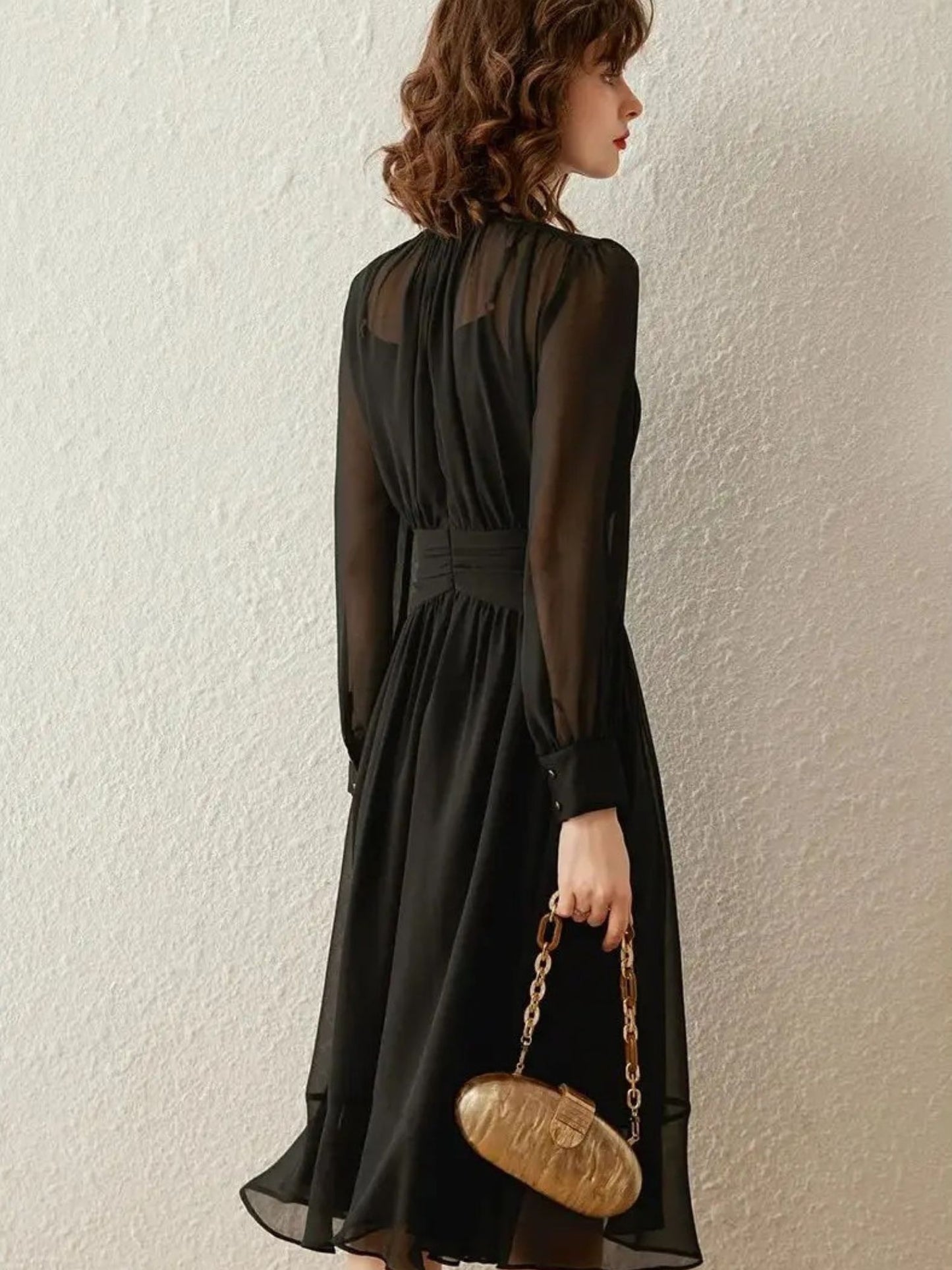 Back view of black long-sleeve midi dress with flowy pleated skirt