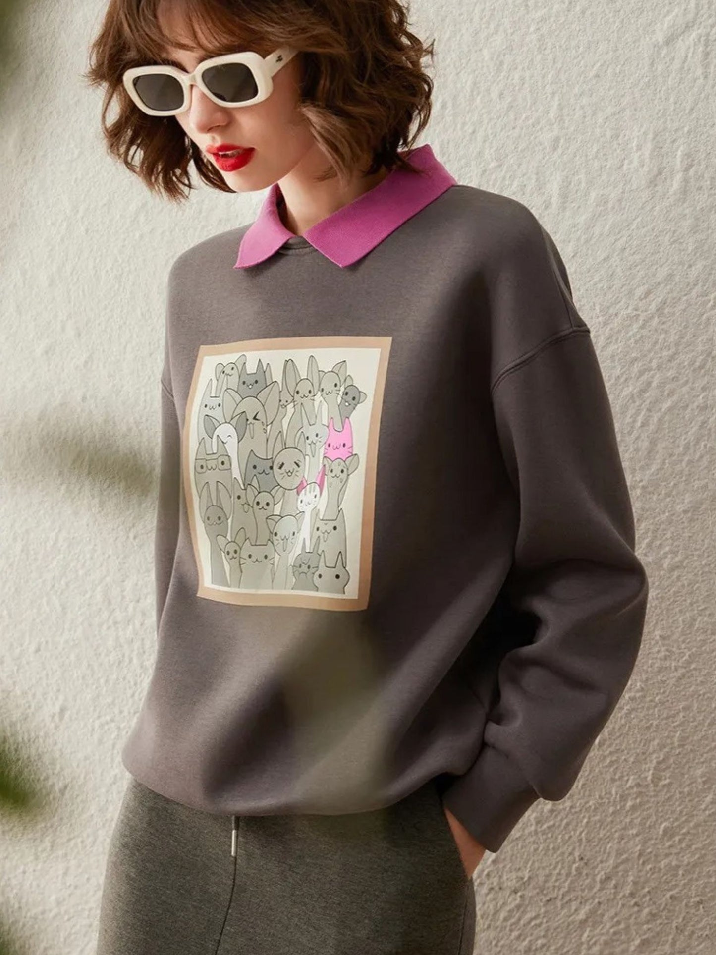 Side angle of grey sweatshirt with front print, paired with pink collared shirt