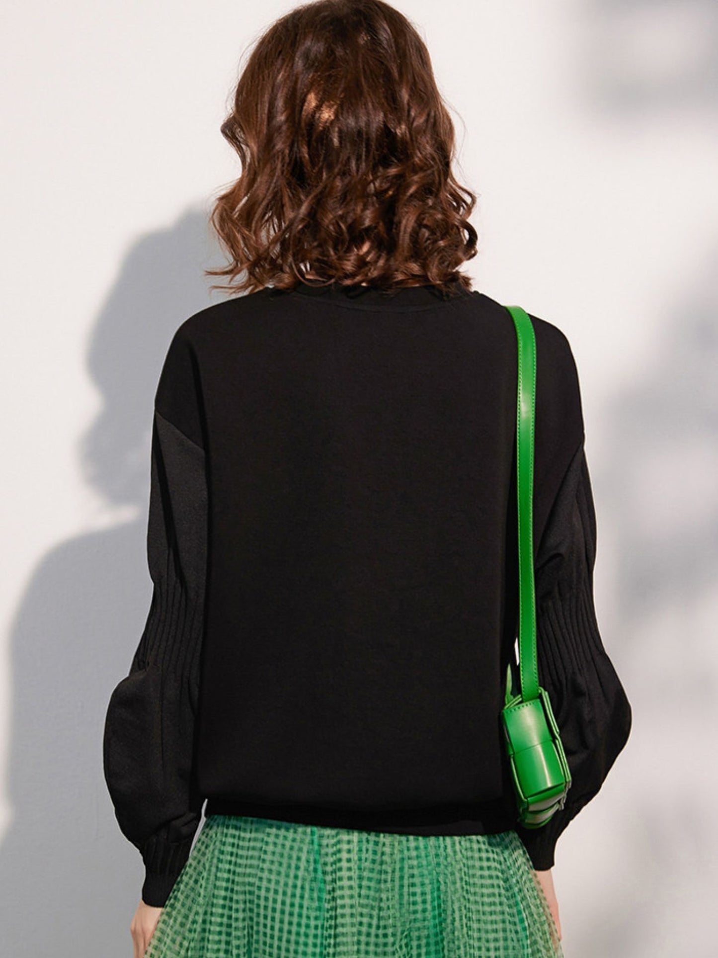 Back view of the woman, showing the rear design and green ribbon detail on the sweatshirt