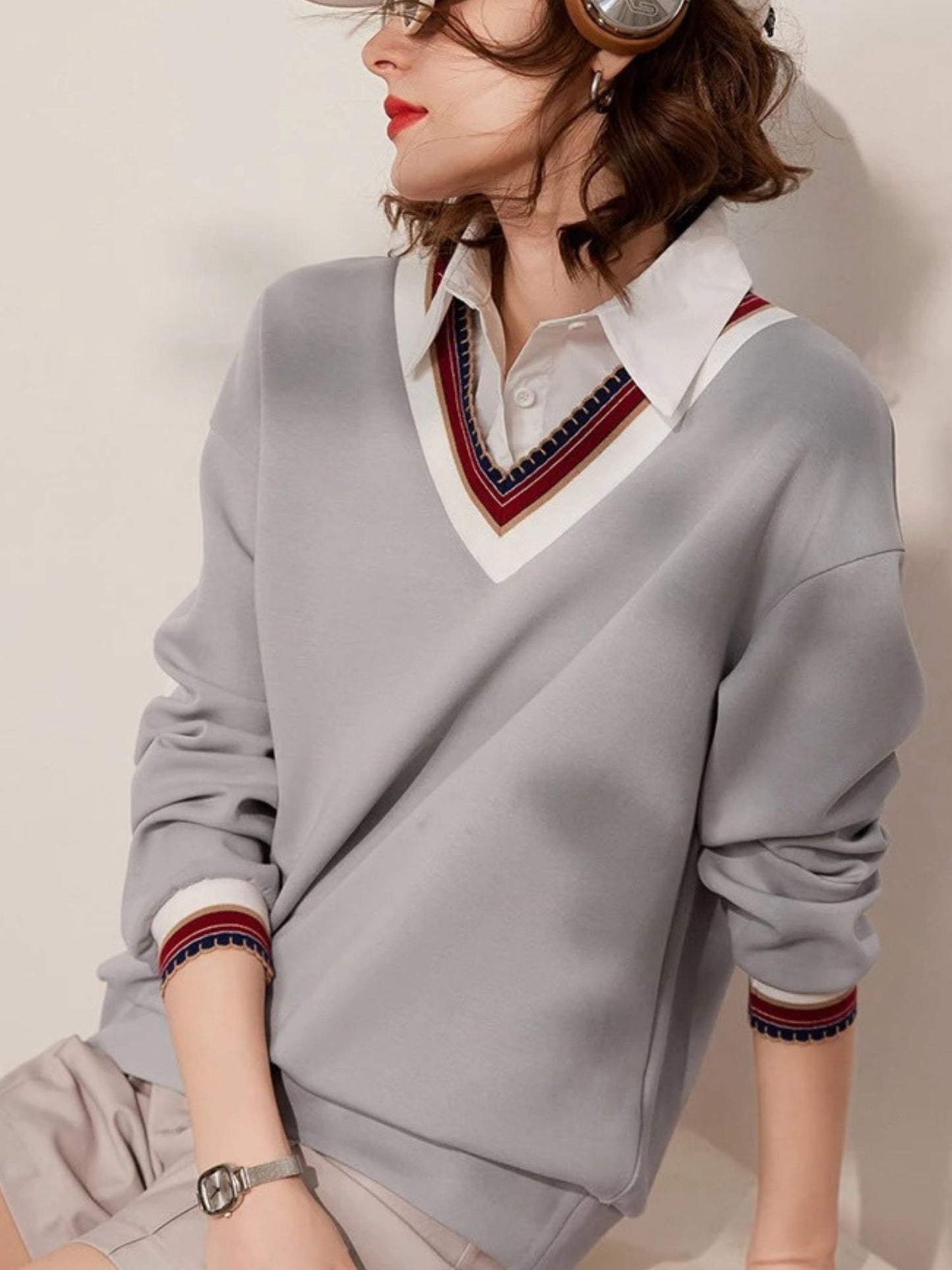Close-up of striped V-neck collar detail on light grey sweatshirt