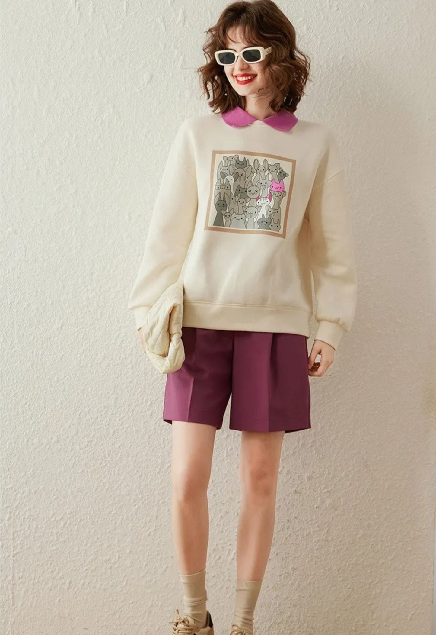 Full body view of ivory sweatshirt with printed front, styled with collared shirt.