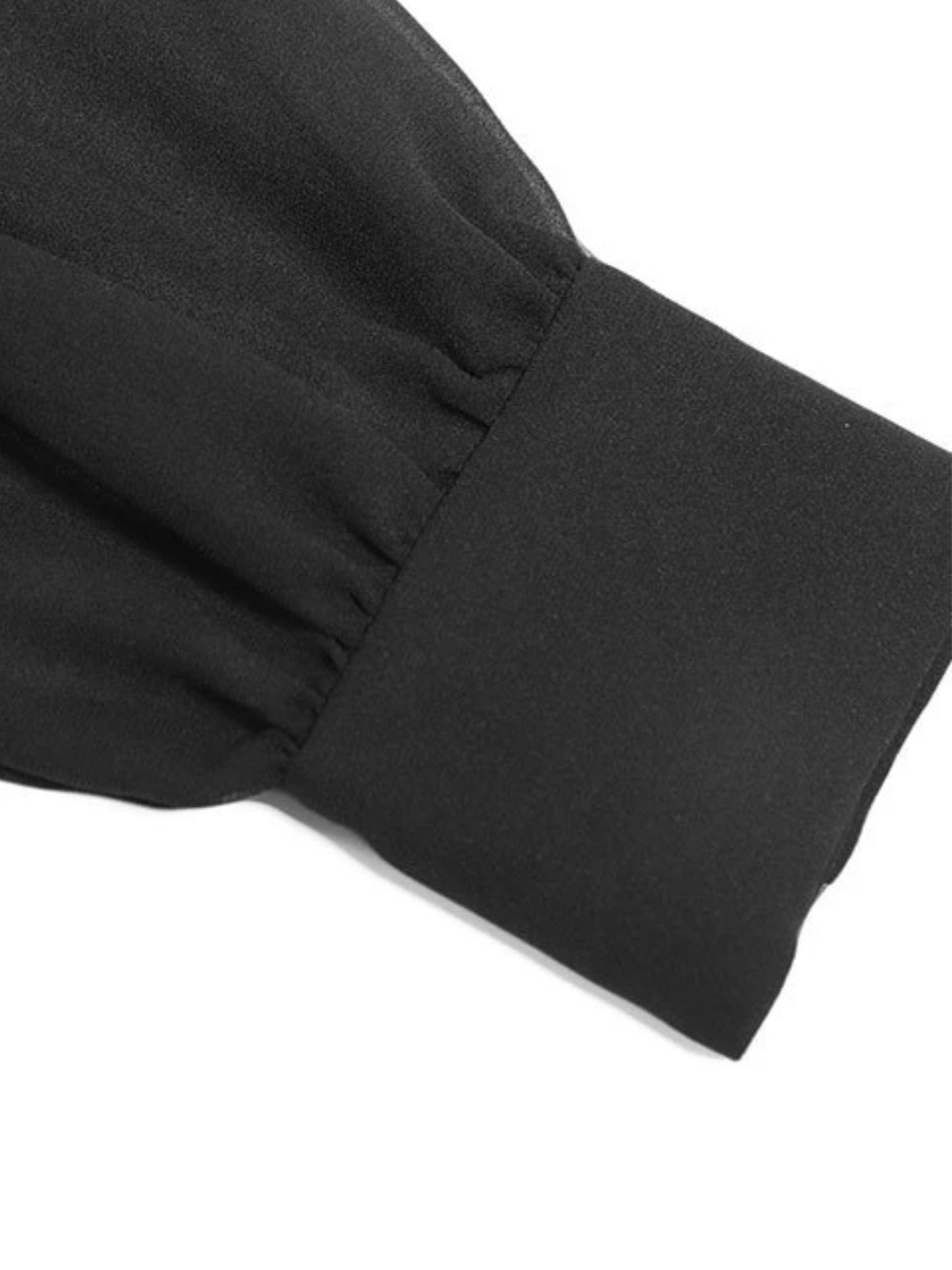 Close up of the sleeve cuff detail of black long-sleeve dress