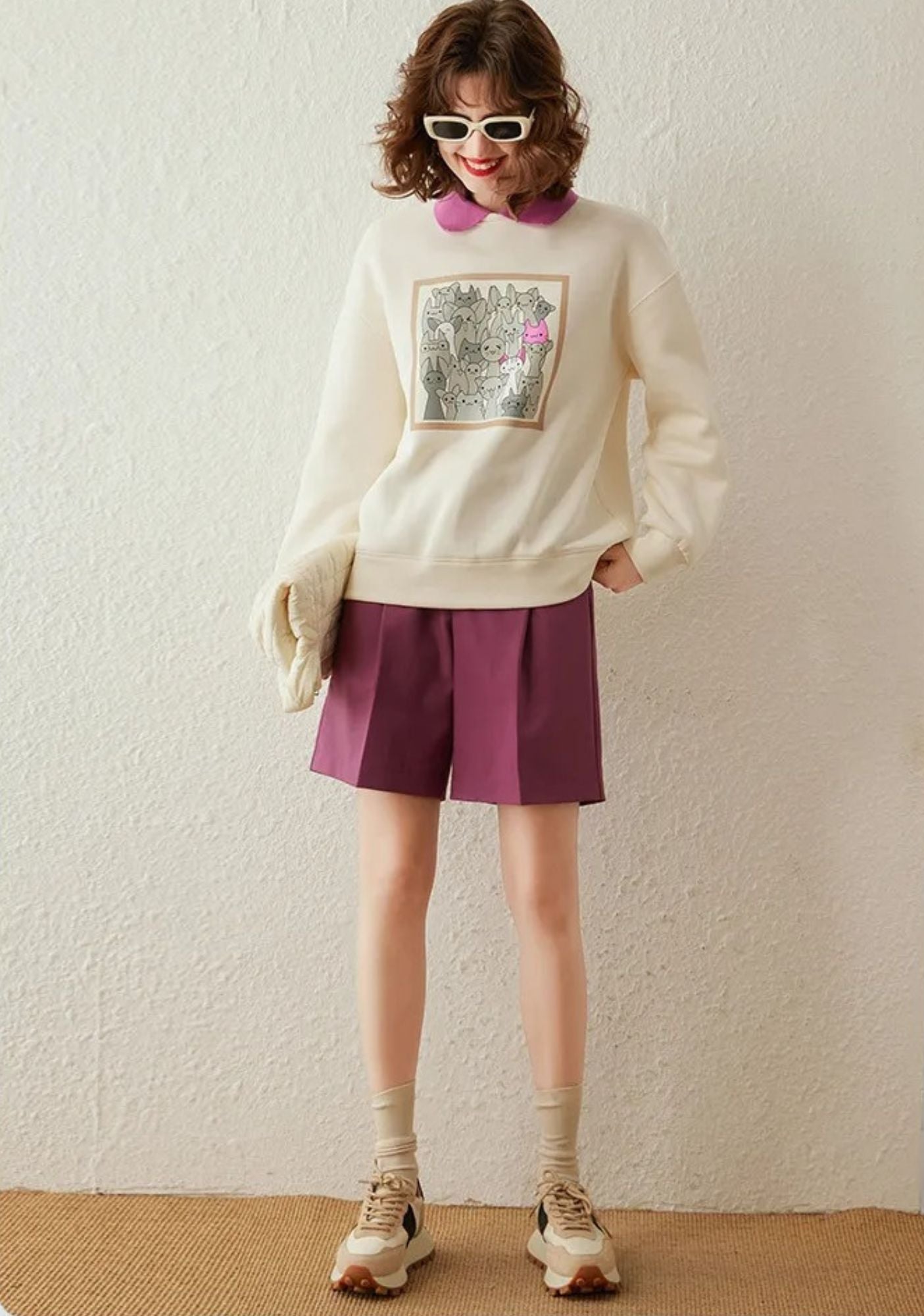 A woman wearing a cream jumper with a contrast polo collar and drop sleeves, featuring a quirky animal print design