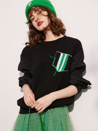 Woman slightly turned to the side, hands in front, showing the design detail on the sweatshirt