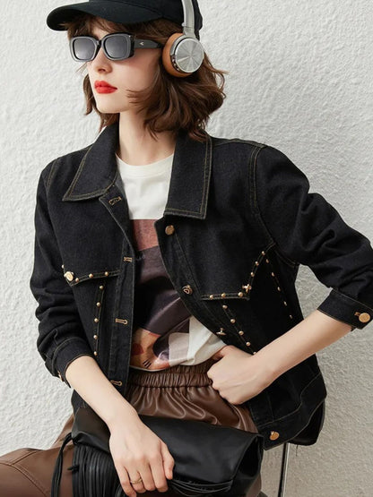 Woman in black denim jacket with gold button details, sunglasses, and headphones, posing with hand on waist