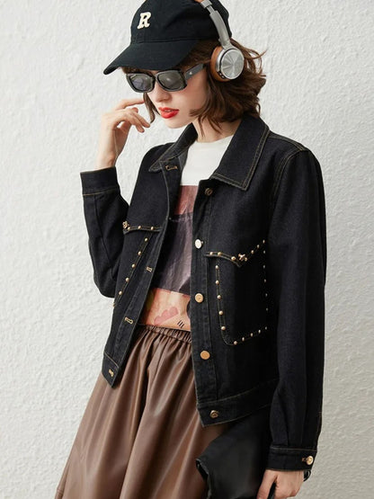 Woman in black denim jacket, sunglasses, and headphones, smiling with relaxed pose