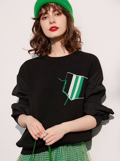 Woman facing forward with hands resting in front, clearly displaying the chest design of the sweatshirt