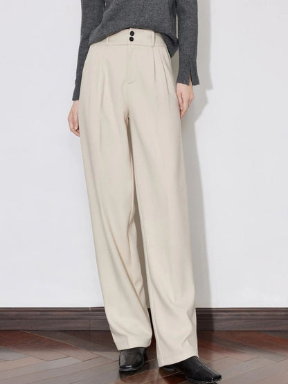 A model wearing a gray sweater with a gray scarf paired with some cream high-waisted pleated trousers