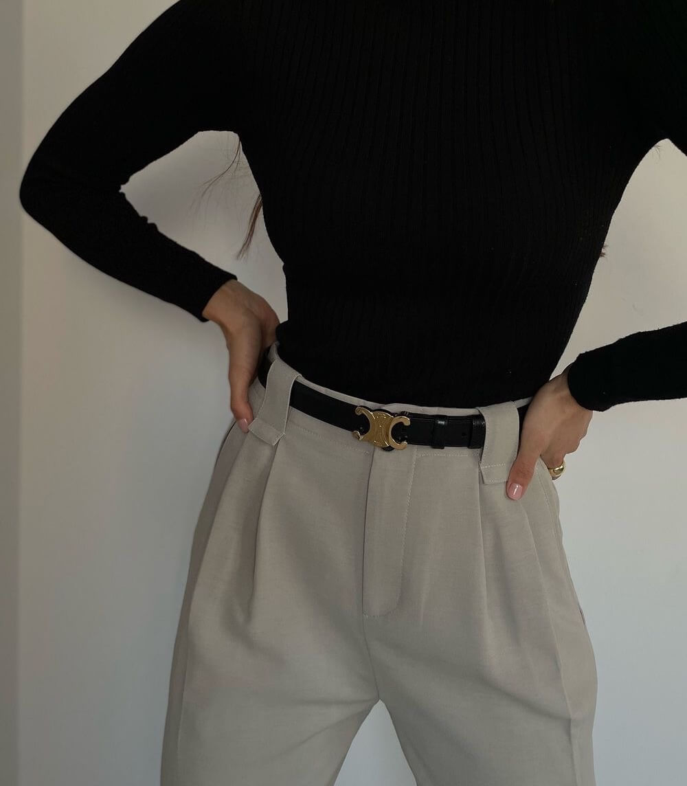 Nahaufnahme einer Frau in schwarzem Strickoberteil, Khakihose und schwarzem Ledergürtel